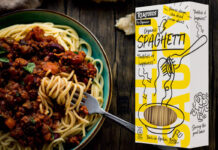 A packet of Realfoods by Oraganico Organic Spaghetti is placed on top of an image of a bowl of spaghetti bolognese.