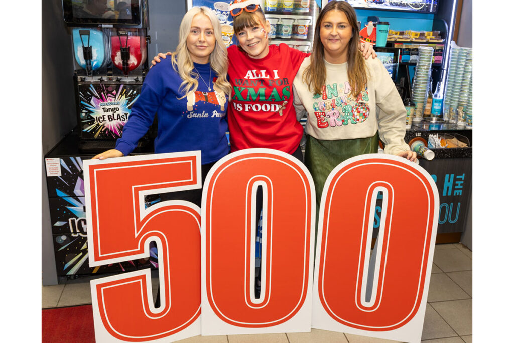 Staff members from Ardgowan Hospice and Spar Greenock stand behind a large 500 sign in the Spar Greenock store.