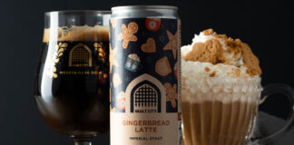 A can of Vault City Gingerbread Latte Stout stands on a table in front of a Vault City branded glass and a bowl with a gingerbread latte in it with whipped cream and gingerbread biscuit.