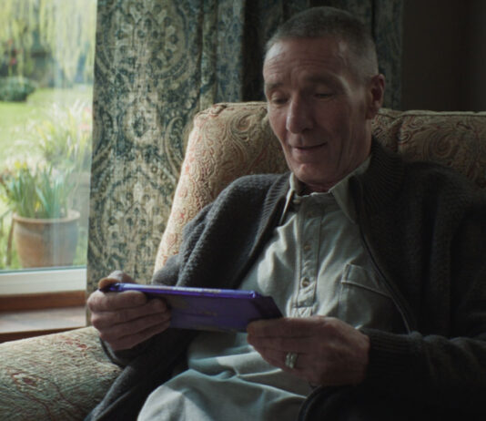Cadbury displays generous nature in new campaign An elderly man sits in a chair by a window holding a large Cadbury Dairy Milk tablet bar.
