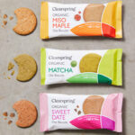 Clearspring launches international trio of oat biscuits Packs of Clearspring Oat Biscuits sit against a grey background including Miso Maple, Matcha and Sweet Date with the biscuits sitting outside the packet with bites taken out of them.