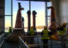 Stills being installed at Eden Mill Distillery with a large window in the background overlooking a waterfront landscape.