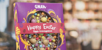 A pack of Gnaw Easter Happy Easter Eggs-travaganza stands upright on a table with a blurred out background.