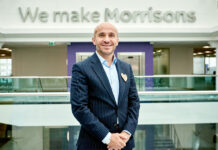 Rami Baitiéh, chief executive of Morrisons, stands in front of a sign that reads 'We make Morrisons' as he is appointed president of GroceryAid.