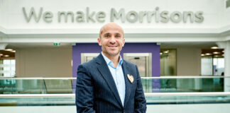 Rami Baitiéh, chief executive of Morrisons, stands in front of a sign that reads 'We make Morrisons' as he is appointed president of GroceryAid.