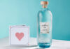 A bottle of Isle of Harris Love Gin stands next to a card with a love heart on it.