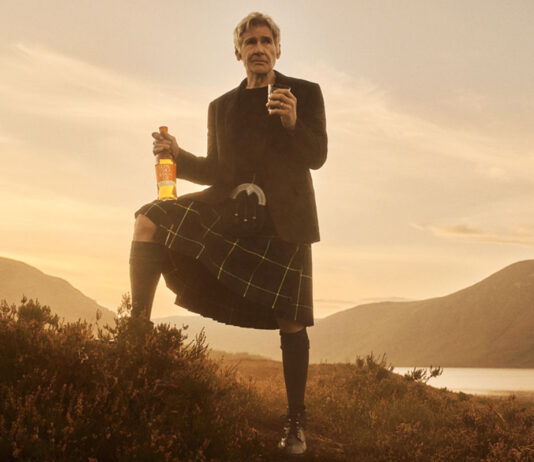 Harrison Ford takes star role in Glenmorangie campaign Hollywood actor Harrison Ford stands against a Highlands landscape during sunset in highland attire holding a bottle of Glenmorangie in one hand and a glass with the whisky inside it in the other.