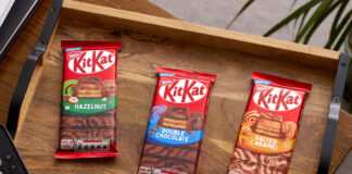 Packs of KitKat sharing bars sit on a wooden tray including KitKat Hazelnut, KitKat Double Chocolate and KitKat Salted Caramel.