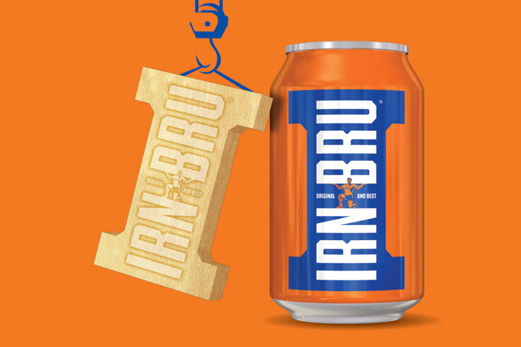 A can of Irn-Bru stands against an orange background with golden Irn-Bru Girder design hangs next to it, suspended by a drawing of a crane.