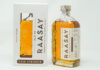 A bottle of Isle of Raasay Cask Strength Third Edition whisky stands next to the packaging for the whisky against a grey background.