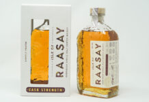 A bottle of Isle of Raasay Cask Strength Third Edition whisky stands next to the packaging for the whisky against a grey background.