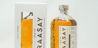 A bottle of Isle of Raasay Cask Strength Third Edition whisky stands next to the packaging for the whisky against a grey background.