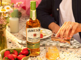 Jameson whiskey unveils new tipple in time for St Patrick’s Day A bottle of Jameson Triple Triple Chestnut Edition is on a table as a person pours out a measure of the whiskey from a jigger into a glass with ice with a vase filled with flowers on the table and a bowl of strawberries.