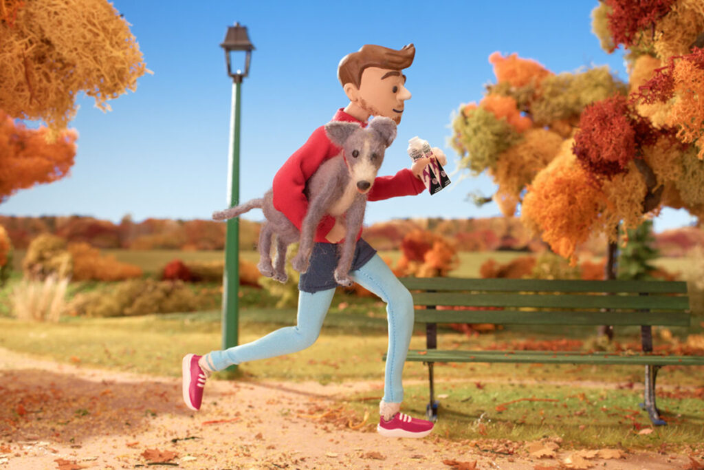 Still image from Nestle Lindahls TV campaign showing an animated man running with a dog in his arm and a Nestle Lindahls Protein Drink in his other hand.