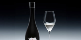 A bottle of Sake ONO stands against a black and white background with a wine glass next to it containing the spirit.