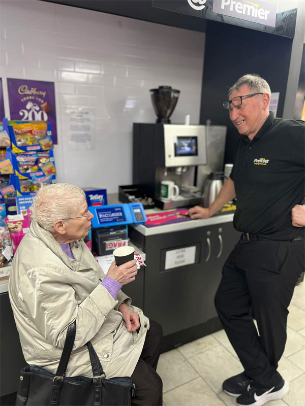 Dennis Williams stands talking to an elderly customer in Premier Broadway Convenience Store.