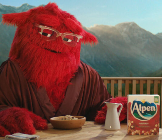 New Alpen mascot campaign to target adult consumers Alpen's mascot 'Mother' sits at a breakfast table with a box of Alpen, a jug for milk and a bowl of muesli in front of her. Mother is a large, red and furry character who wears glasses.