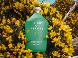 Holyrood Distillery secures listing for gin A bottle of Height of Arrows gin lies in a bush of yellow flowers.