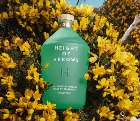 Holyrood Distillery secures listing for gin A bottle of Height of Arrows gin lies in a bush of yellow flowers.