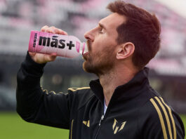 Messi launches Más+ by Messi drinks exclusively in Spar Lionel Messi drinks from a Mas+ by Messi Miami Punch drink in a football stadium.