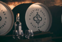 A whisky cask with the Saltire Rare Malt Whisky brand on the top of the lid with a bottle of whisky and nosing glasses in the foreground of the image.