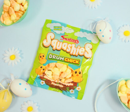 Swizzels refreshes Squashies Easter sweets A packet of Swizzels Squashies Drumchick sits on a blue table with baskets filled with the sweets around the packet with small toy eggs around the packet.