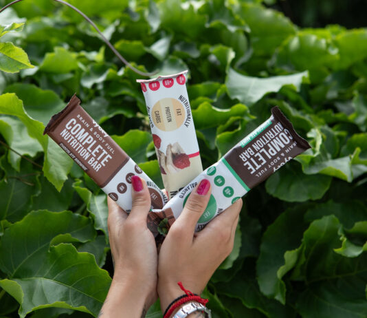 Vybey enters healthy snacks fray with Nutrition bars A person holds Vybey's three nutrition bars – Chocolate Brownie, Raspberry White Chocolate and Mint Chocolate – with a green bush behind the bars.