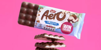 A bar of Aero Coconut Sharing is above halved pieces of the chocolate bar that have been stacked on top of each other against a pink background.
