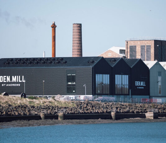 Production kicks off at Eden Mill distillery A photograph of the Eden Mill Distillery in St Andrews looking over a body of water to the distillery and its warehouses.