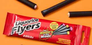 A pack of Liquorice Flyers Four Pack lies against an orange background with single Flyers sweets scattered around the packet.