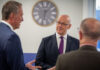 First Minister of Scotland John Swinney stands talking to two men at the Highland Spring Group's Blackford site in Perthshire.