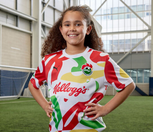 Kellogg’s Football Camps kick off for 2025 A young girl stands on a football pitch wearing the Kellogg's x Puma football top.