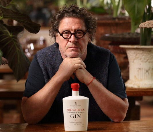 Marco Pierre White gin rolls out to Sainsbury’s stores Marco Pierre White sits at a table with his hands resting under his chin with a bottle of Mr White's Gin on the table under his chin.