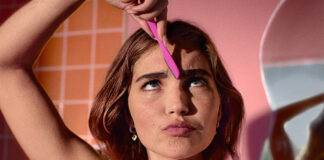 A woman uses Wilkinson Sword Intuition Eyebrow Shaper whilst pursing her lips in a comical manner in a bathroom.
