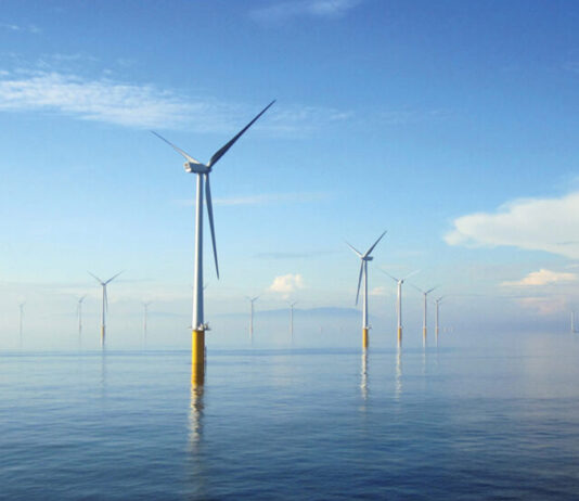 Scotmid secures 10 year green energy deal A range of wind turbines across a stretch of the sea.