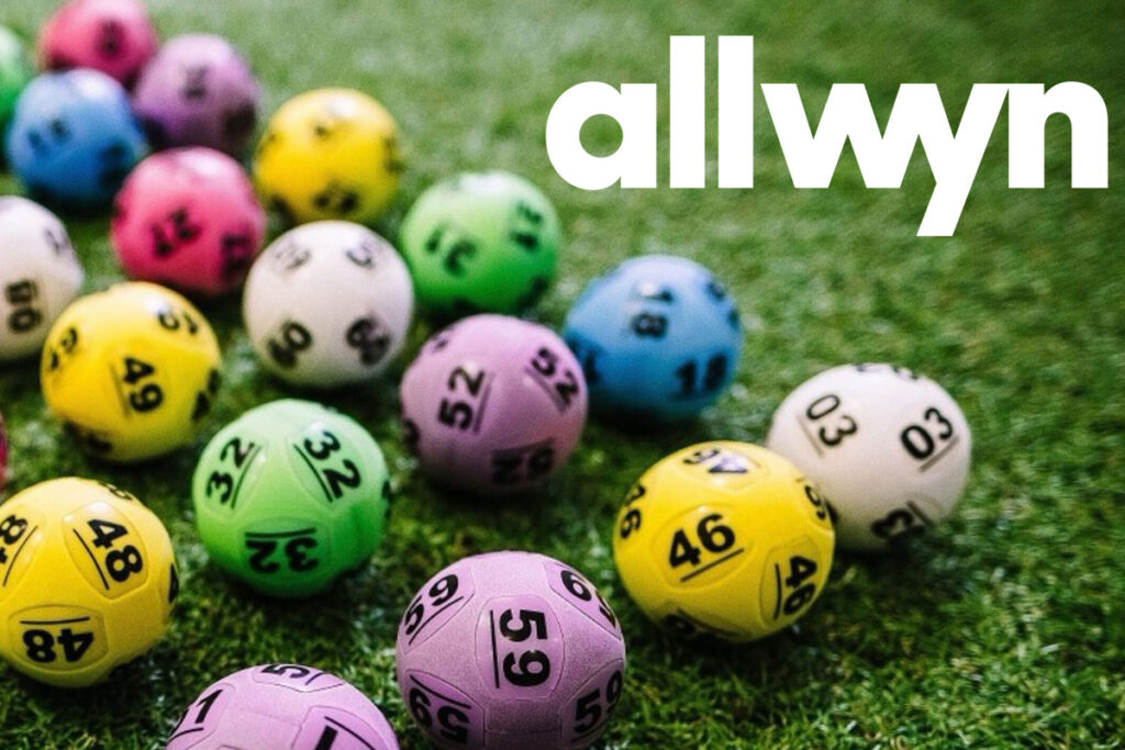 Multi-coloured National Lottery balls lie on grass with the Allwyn logo in the top right hand corner.
