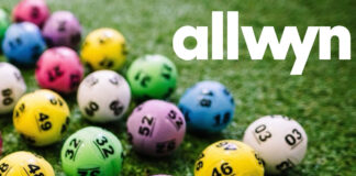 Multi-coloured National Lottery balls lie on grass with the Allwyn logo in the top right hand corner.