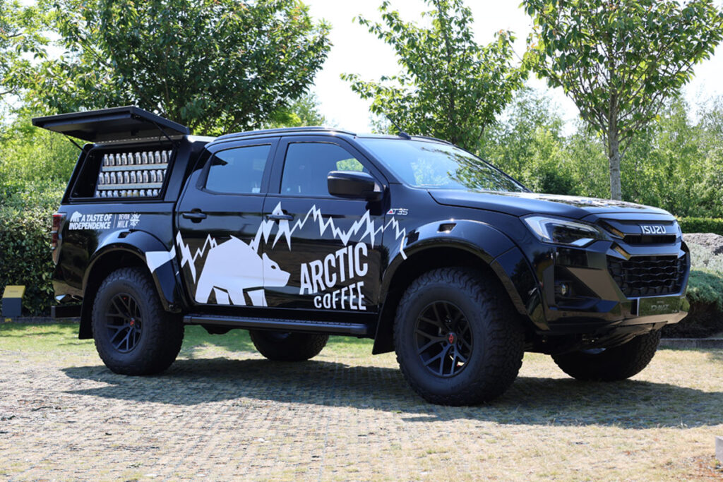 An Arctic Coffee branded Izuzu D-Max Arctic Truck is parked with its side window open with bottles of the chilled coffee available for sale.