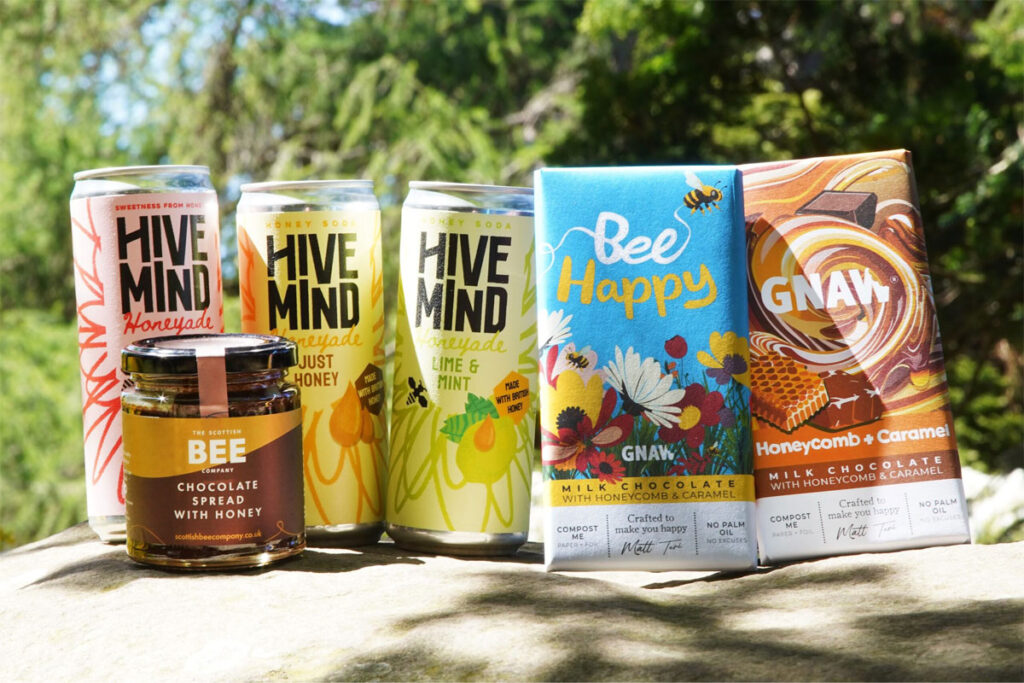 Cans of Hive Mind Honeyade, The Scottish Bee Company Chocolate Spread with Honey jar and bars of GNAW Chocolate with Honeycomb and Caramel are all grouped together to mark World Bee Day.