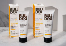 Packs of Bulldog Anytime Daily UV Moisturiser SPF 50 and Bulldog Anytime Daily UV Moisturiser SPF 30 with the tubes of cream standing outside the outer packs on a white table with their shadows casted onto a white wall behind the products.
