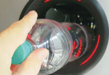 A person is putting an empty plastic bottle into a reverse vending machine.