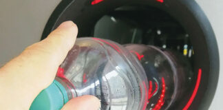 A person is putting an empty plastic bottle into a reverse vending machine.