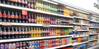 A range of soft drinks sitting in chillers in a store.
