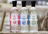 Bottles of Eden Mill's core gin range stand on a wall including Eden Mill Love Gin, Eden Mill Original Gin and Eden Mill Golf Gin.