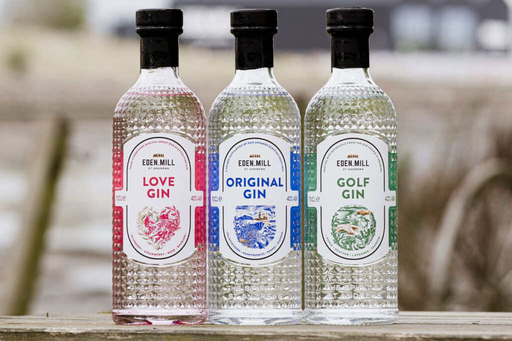 Bottles of Eden Mill's core gin range stand on a wall including Eden Mill Love Gin, Eden Mill Original Gin and Eden Mill Golf Gin.