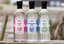 Bottles of Eden Mill's core gin range stand on a wall including Eden Mill Love Gin, Eden Mill Original Gin and Eden Mill Golf Gin.