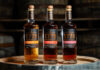 Bottles of Glasgow 1770 Small Batch Series Wine Cask editions including Constantia Wine Cask Matured, Syrah Wine Cask Matured and Pineau des Charentes Wine Cask Matured. All three bottles stand on top of a wooden barrel.