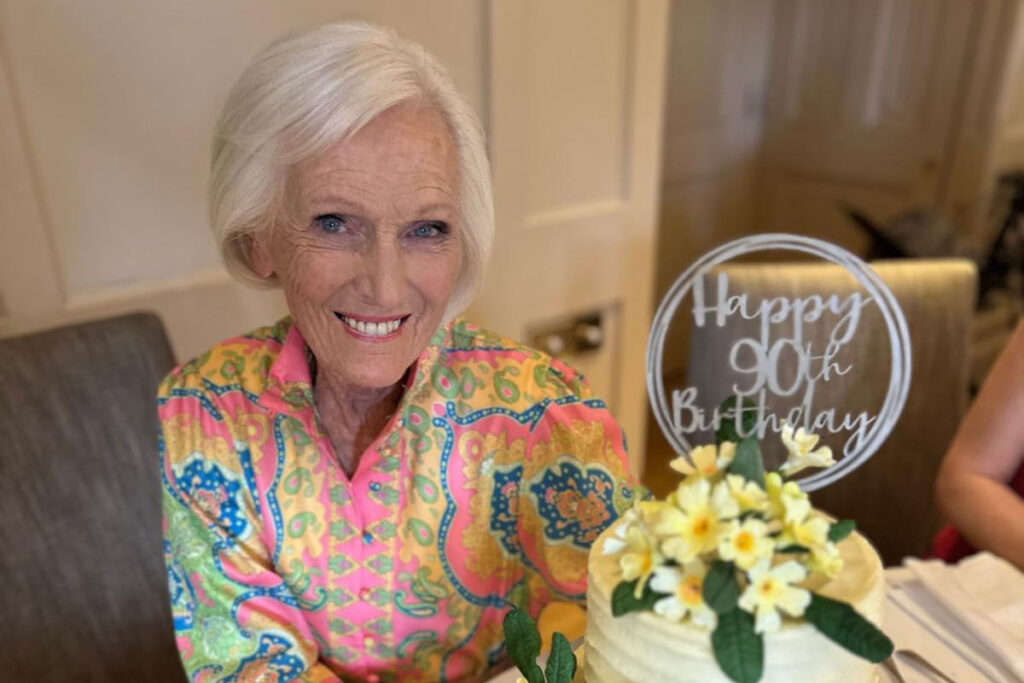TV personality and baker Mary Berry sits at a table with the 90th Birthday cake that Finsbury Food Group had made for her.