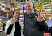 Natalie and Martin Lightfoot stand inside their store Londis Solo Convenience in Baillieston with crossed fingers to mimic the National Lottery mascot.