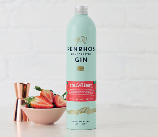 Penrhos Gin unveils new Wonky Strawberry Gin flavour A bottle of Penrhos Handcrafted Wonky Strawberry Gin stands on a white table against a white background with a pink bowl of strawberries next to the bottle and a rose gold jigger measure behind the bowl.